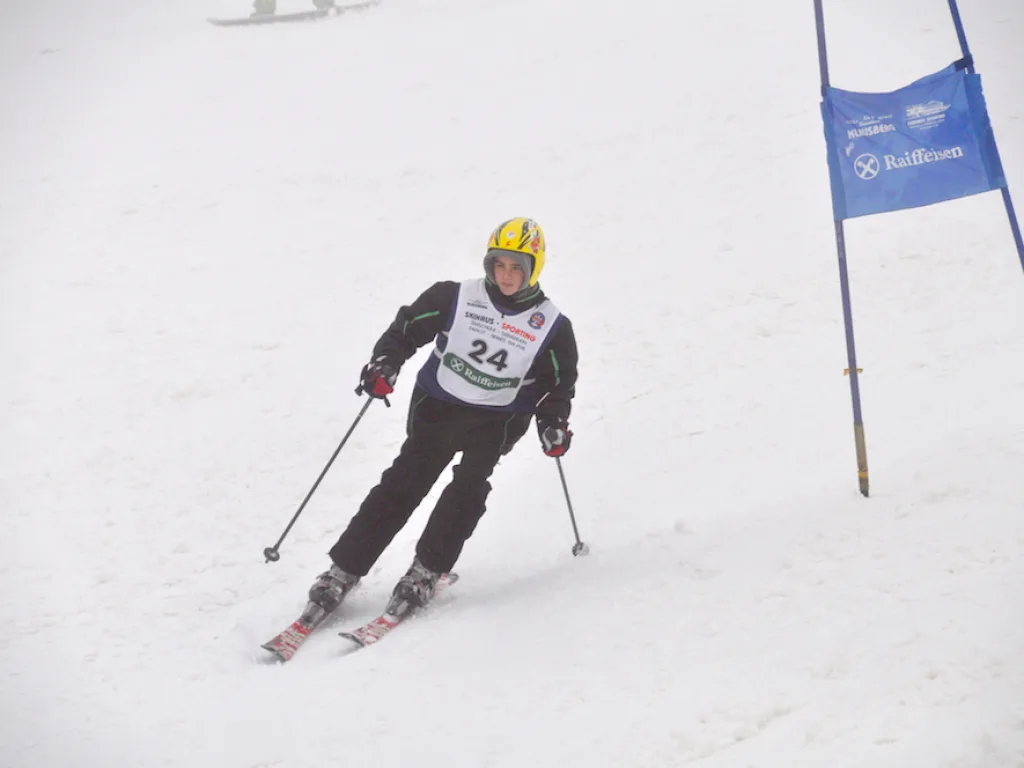 Skifahrerin mit gelbem Helm am blauen Tor.